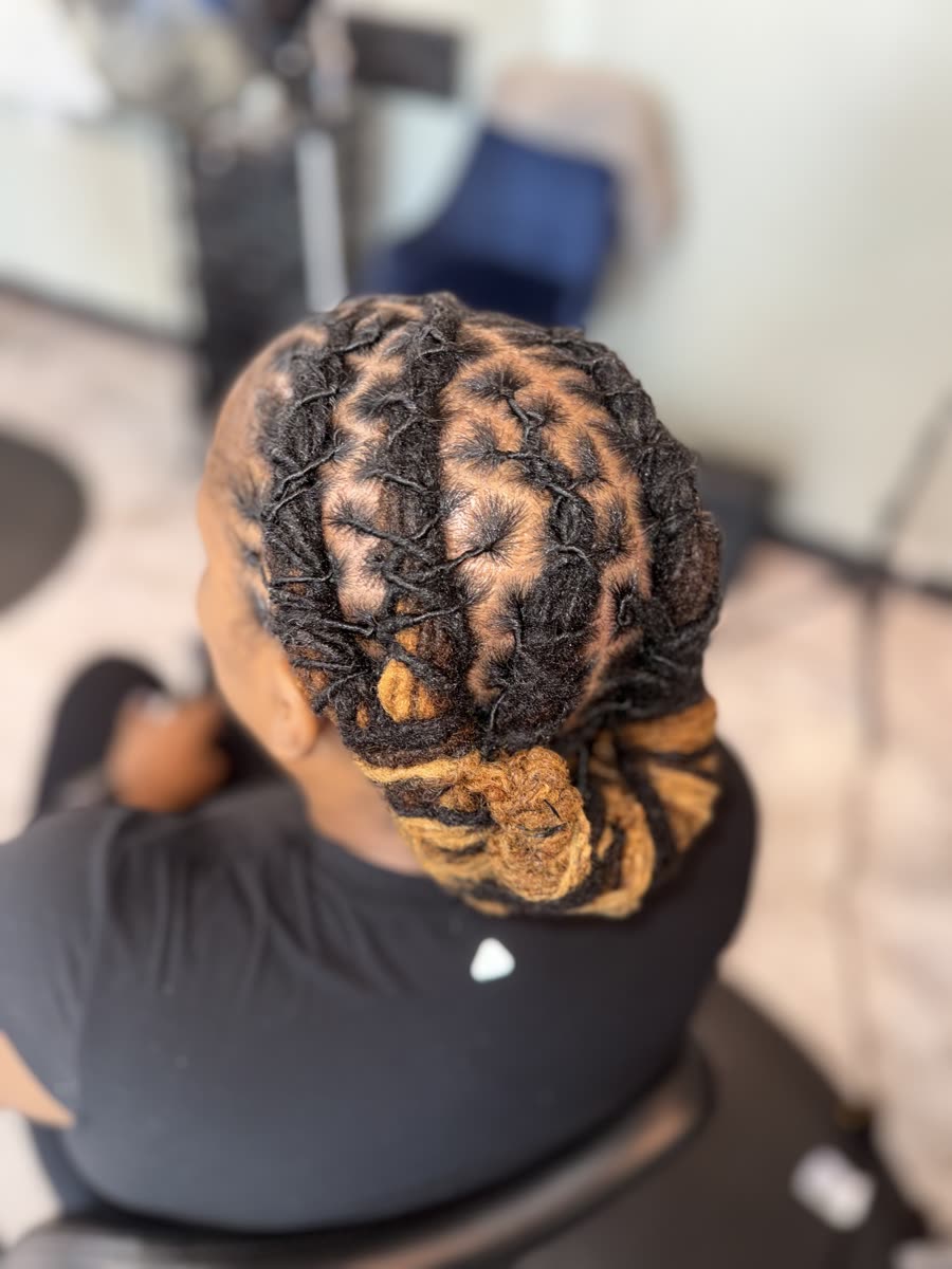 Retwist with gold color accent styled in an updo bun