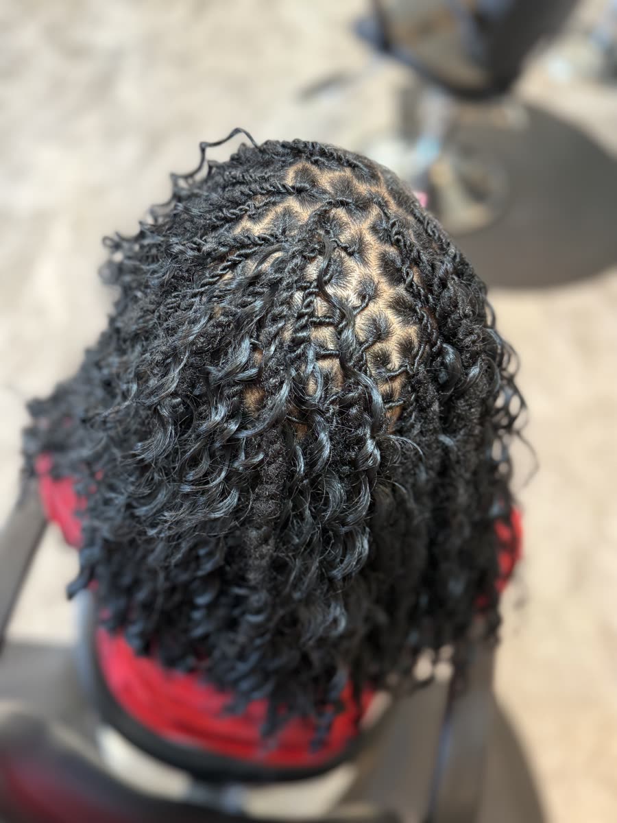 Kids cornrows styled into a top bun